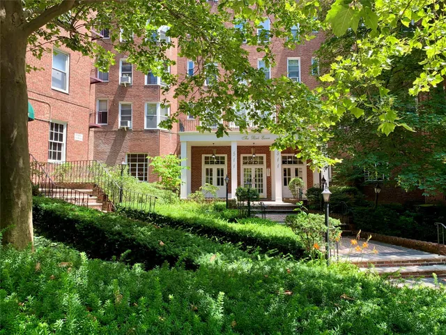 a view of a house with brick walls and a yard with plants and trees