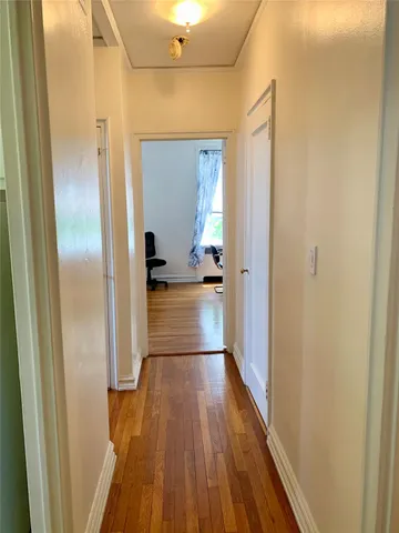 a view of a hallway with wooden floor and a bathroom