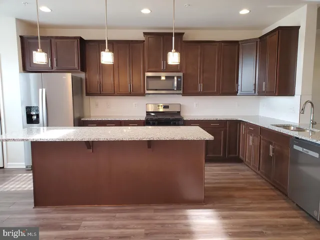 a kitchen with stainless steel appliances granite countertop a sink a stove a refrigerator and wooden cabinets