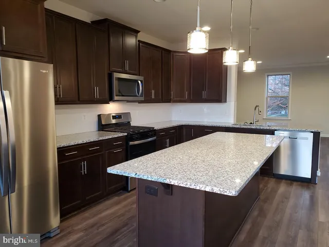 a kitchen with kitchen island granite countertop wooden cabinets and a refrigerator