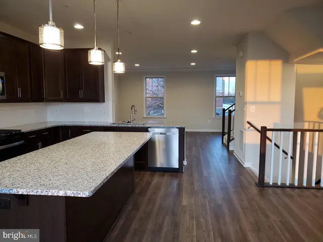 a kitchen with center island wooden floor appliances and a window