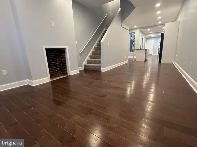 an empty room with wooden floor and stairs