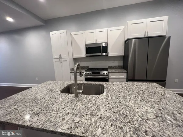 a kitchen with granite countertop a refrigerator and a stove top oven
