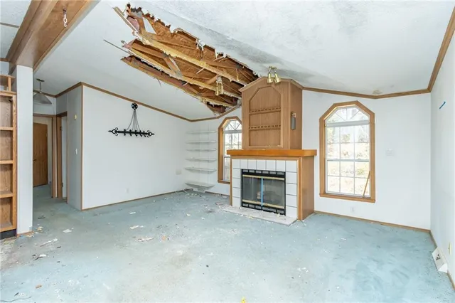 an empty room with windows fireplace and fans
