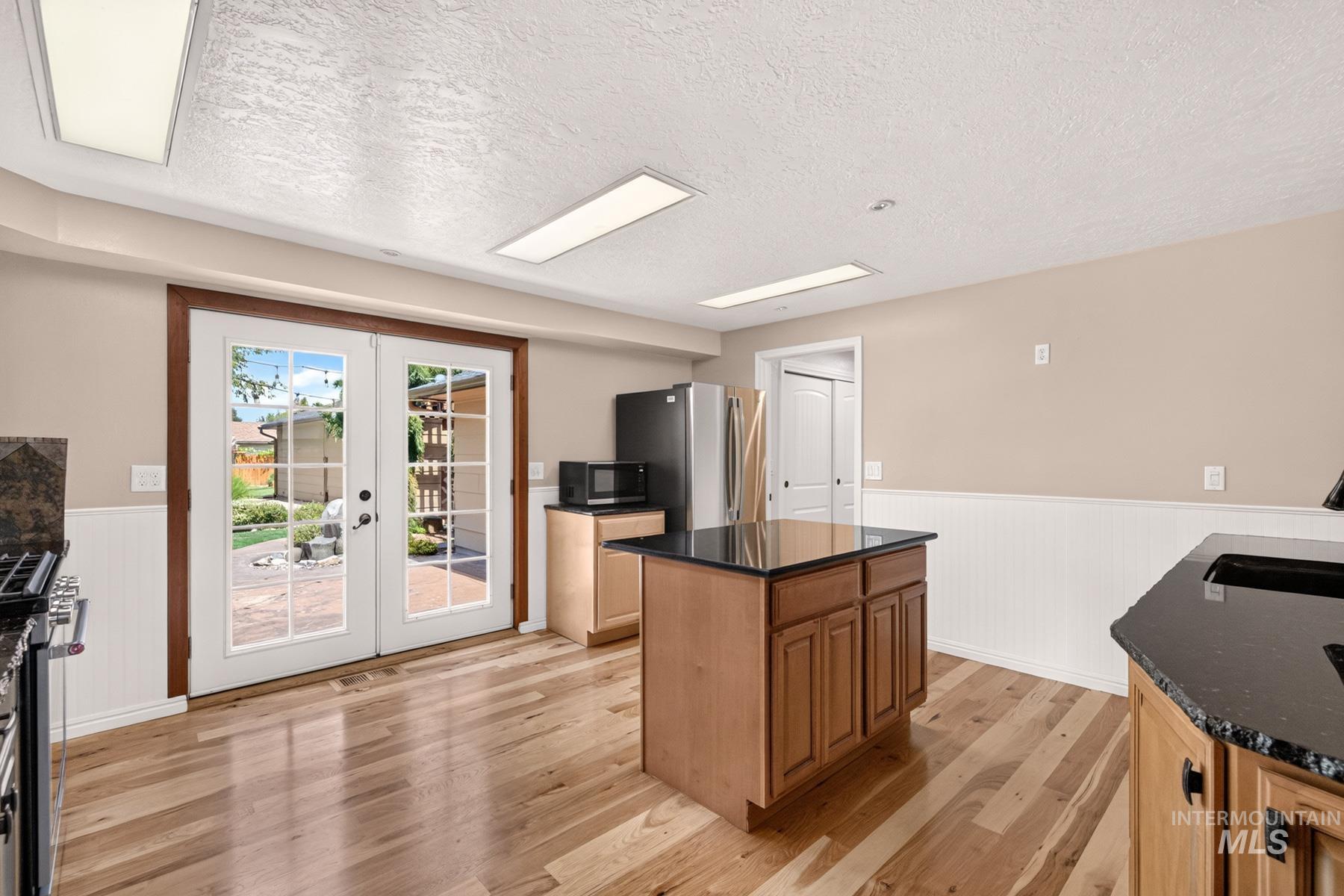 9622 Delaware Street Boise, ID 83709 - Photo 14 of 48 Kitchen space featuring wood-finish flooring, a central island with dark countertops, and light wood cabinetry