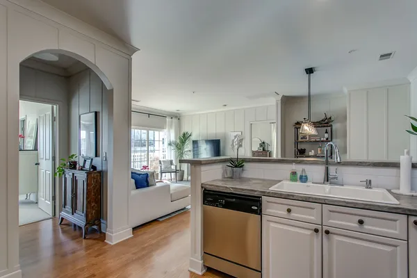 a kitchen with kitchen island granite countertop a sink cabinets and wooden floor