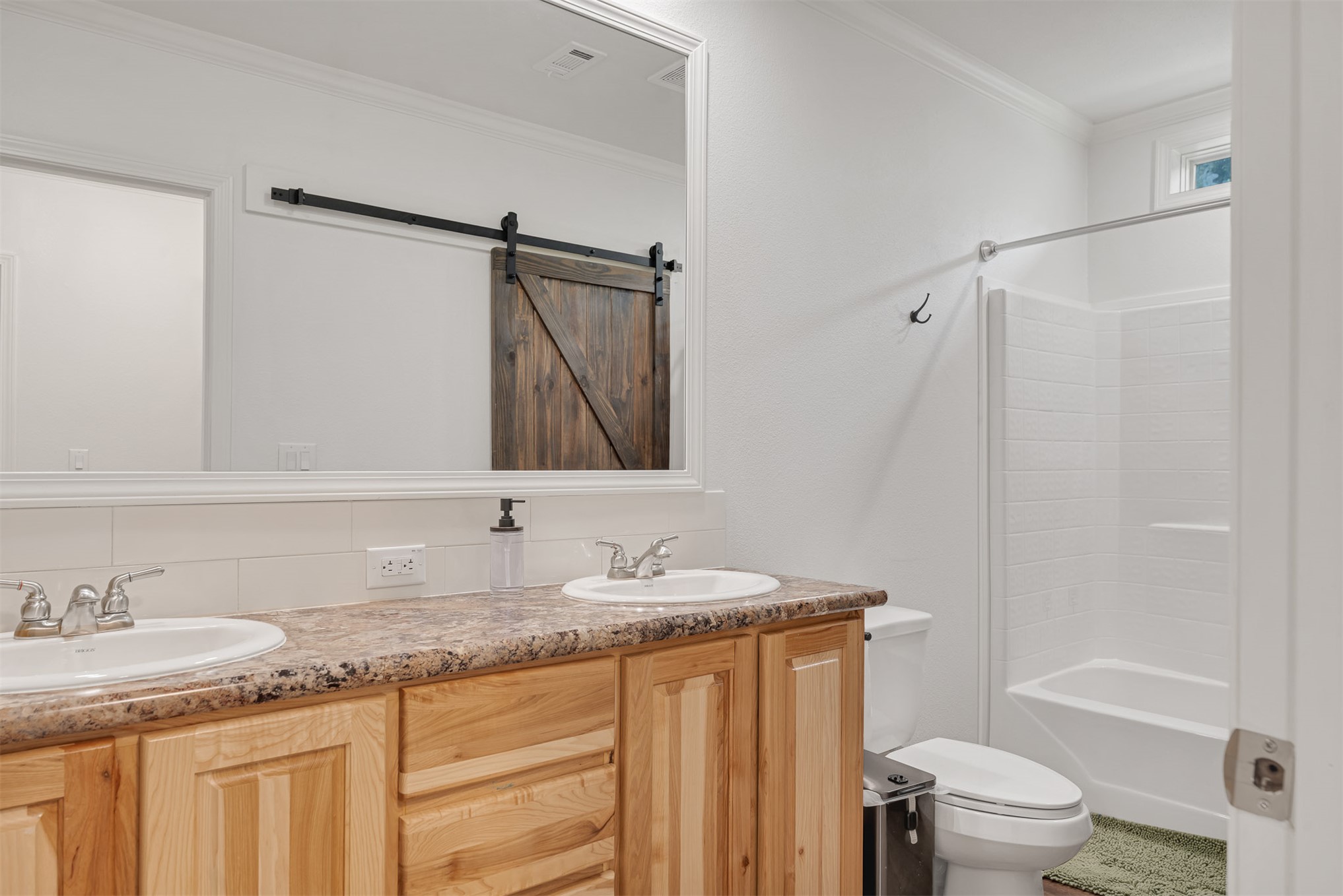 15291 East 400 Road Claremore, OK 74017 - Photo 42 of 96 Dual basin vanity with wood-finish cabinetry, a patterned countertop, and a full-width mirror