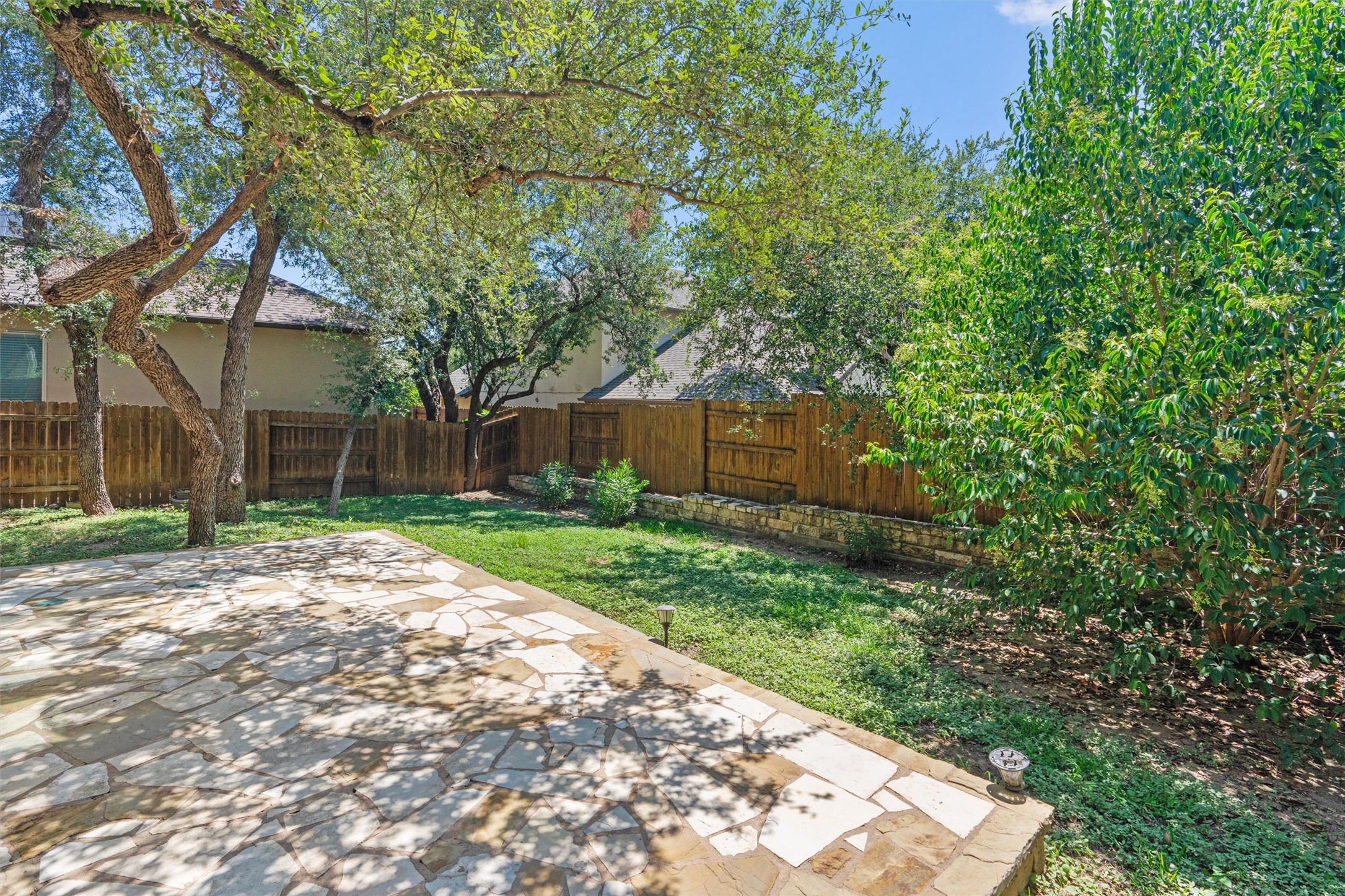 8417 Etienne Cove Austin, TX 78759 - Photo 31 of 35 A spacious backyard unfolds, featuring a flagstone patio, lush lawn, and mature trees providing ample shade.