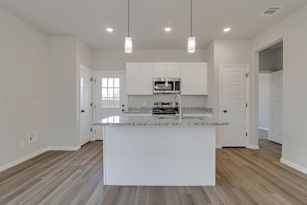 1520 Whippoorwill Way Azle, TX 76020 - Photo 11 of 25 a kitchen with stainless steel appliances granite countertop a sink a stove a refrigerator and a oven with wooden floor