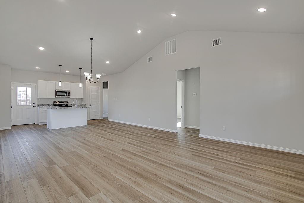 1520 Whippoorwill Way Azle, TX 76020 - Photo 8 of 25 an empty room with wooden floor and kitchen view