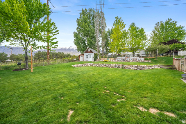 357 South 320 W Street Lindon, UT 84042 - Photo 31 of 41 Expansive green lawn with tiered landscaping, defined by a stone retaining wall