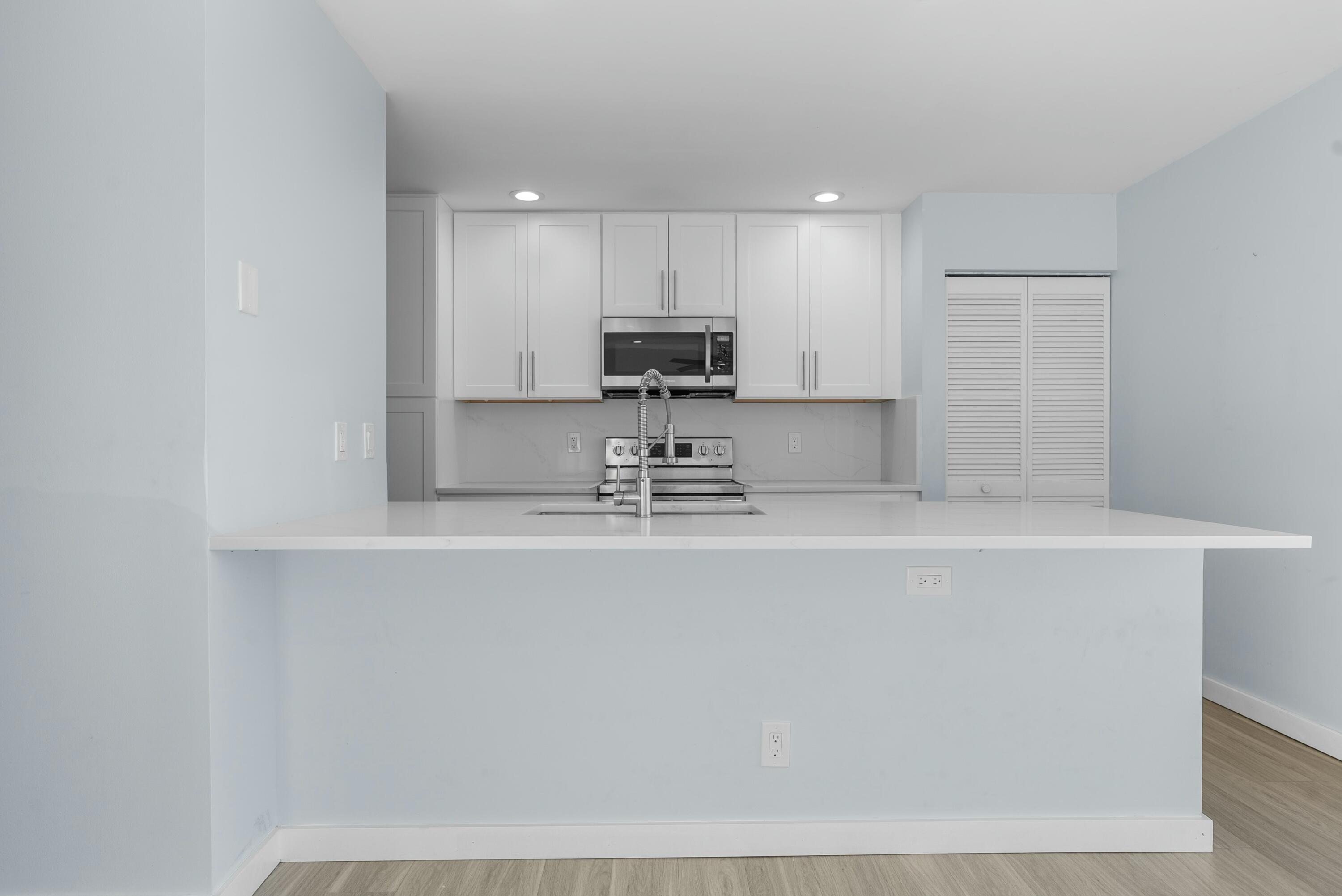 210 Ocean Dunes Circle Jupiter, FL 33477 - Photo 18 of 43 a kitchen with kitchen island a sink a stove a refrigerator and white cabinets