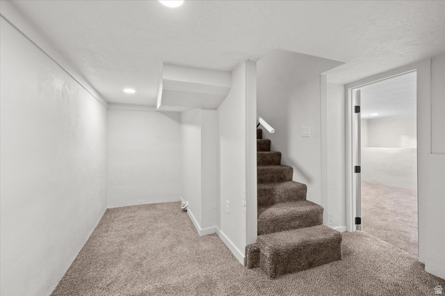 327 35th Street Ogden, UT 84401 - Photo 25 of 31 Carpeted interior space featuring a staircase with a white handrail, recessed lighting, white walls, and a doorway opening to an additional room