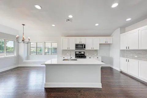 a large kitchen with stainless steel appliances a large center island attached withe living room