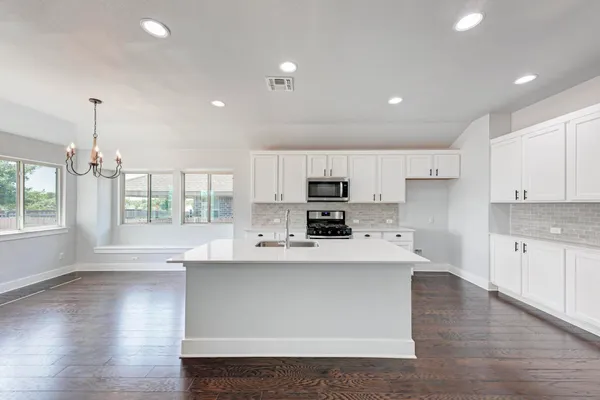 a large kitchen with stainless steel appliances a large center island attached withe living room