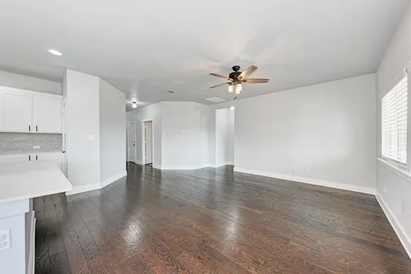 a view of an empty room with a window and wooden floor