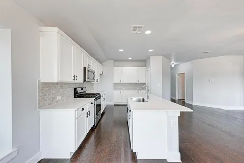 a large kitchen with stainless steel appliances kitchen island a stove a sink a refrigerator and a cabinets