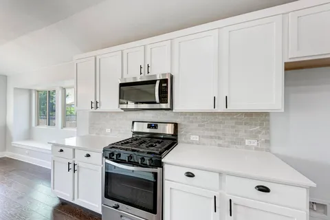 a kitchen with white cabinets and appliances