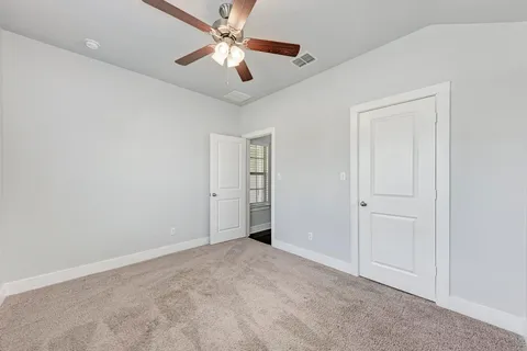 an empty room with closet and a ceiling fan