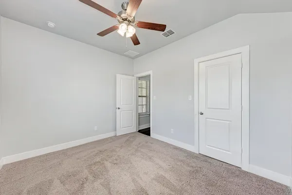an empty room with closet and a ceiling fan
