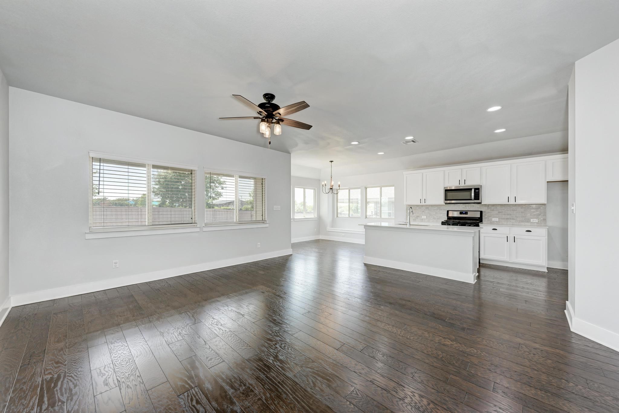 189 Tailwind Drive Kyle, TX 78640 - Photo 4 of 40 a view of an empty room with wooden floor and a kitchen