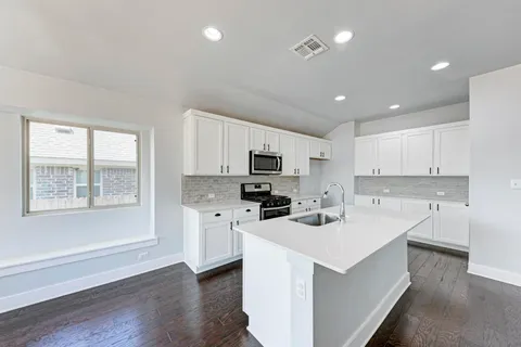 a kitchen with a sink a counter top space stainless steel appliances and cabinets