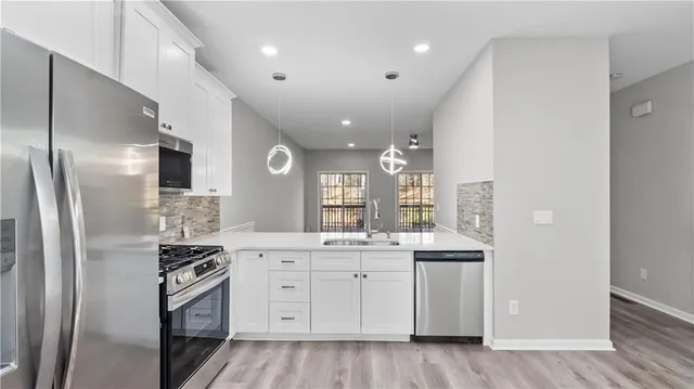 a kitchen with stainless steel appliances granite countertop a stove a refrigerator and a sink with white cabinets