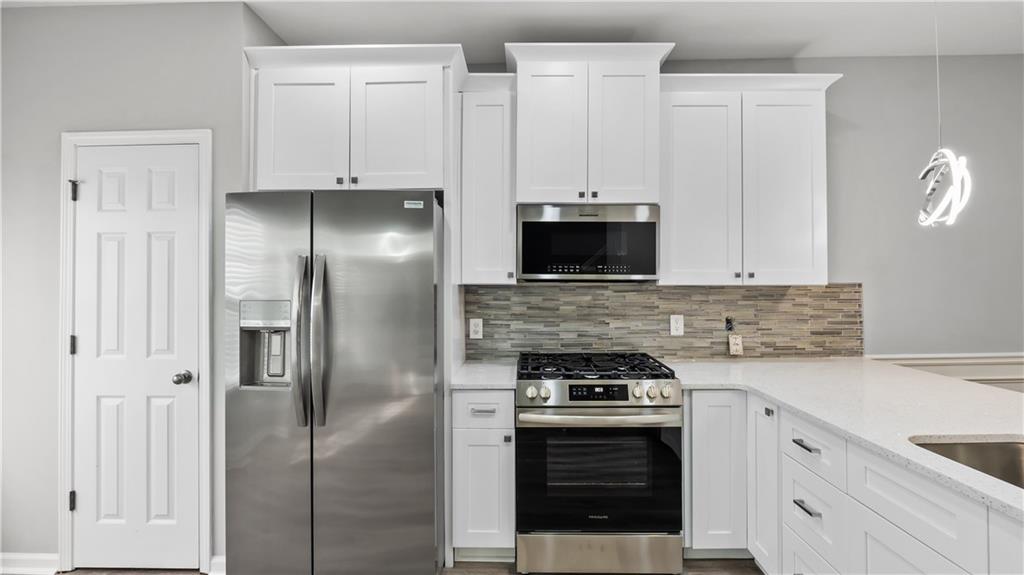 2793 Keystone Avenue Lithonia, GA 30058 - Photo 18 of 33 a kitchen with stainless steel appliances granite countertop a stove a refrigerator and a sink with white cabinets