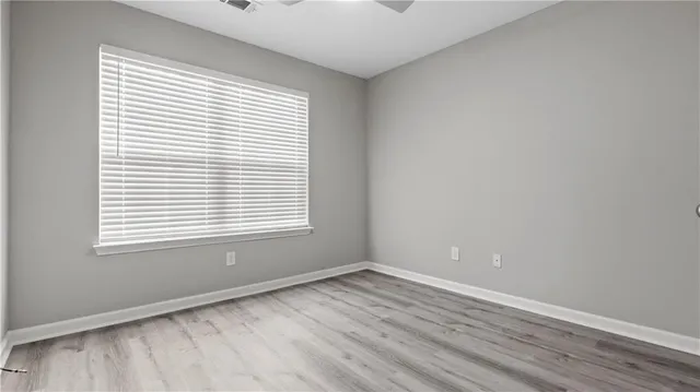 a view of an empty room with wooden floor and closet