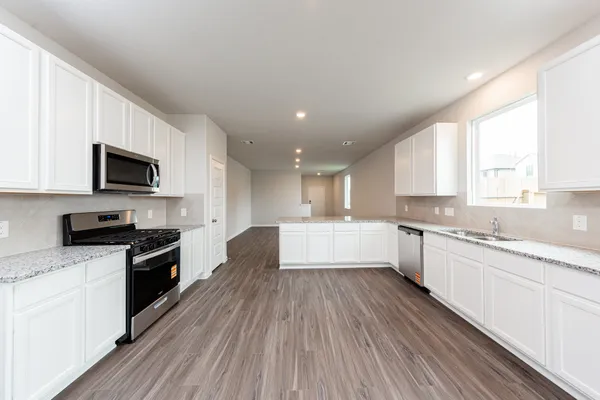a large kitchen with granite countertop a large counter top space a sink stainless steel appliances and cabinets