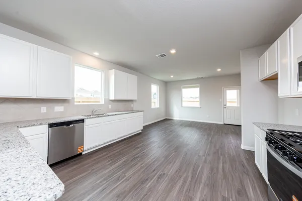 a large kitchen with cabinets wooden floor and stainless steel appliances