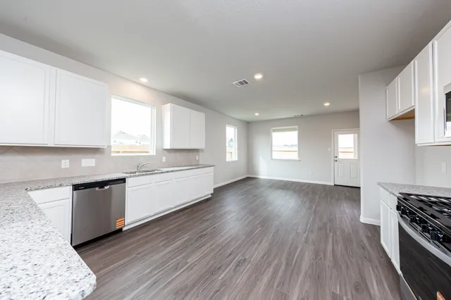 a large kitchen with cabinets wooden floor and stainless steel appliances