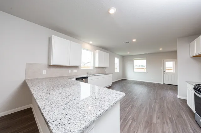 a view of a kitchen with kitchen island a sink wooden floor and counter space