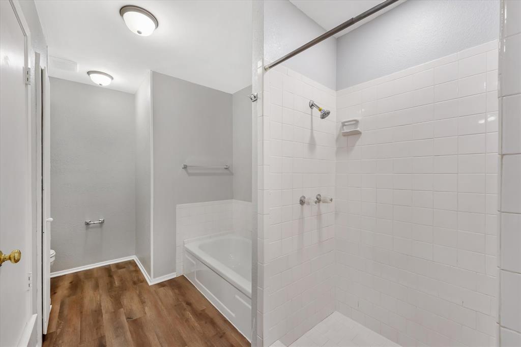 4005 Ridgebrook Drive Arlington, TX 76015 - Photo 15 of 18 Bathroom featuring a white subway tile shower, built-in bathtub, and wood-finish flooring