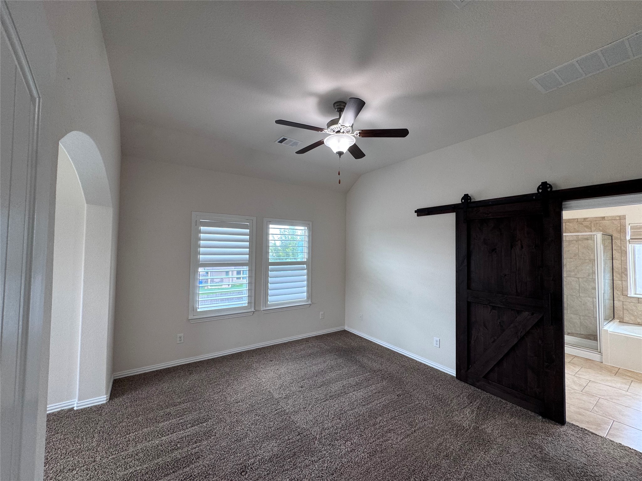 2605 Rough Berry Road Pflugerville, TX 78660 - Photo 29 of 40 A well-lit primary bedroom features soft carpet flooring and a stylish barn door leading to an en-suite.