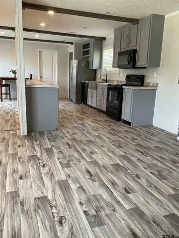 a living room with stainless steel appliances kitchen island granite countertop a refrigerator stove top oven and sink