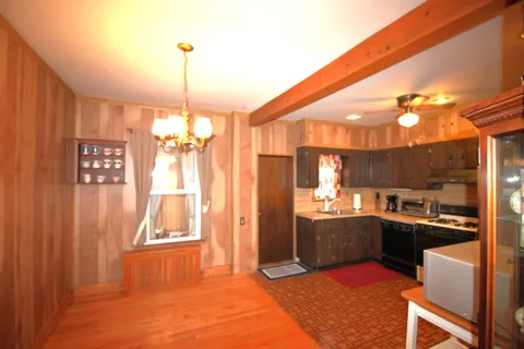 a kitchen with stainless steel appliances granite countertop a refrigerator a sink dishwasher a dining table and chairs with wooden floor