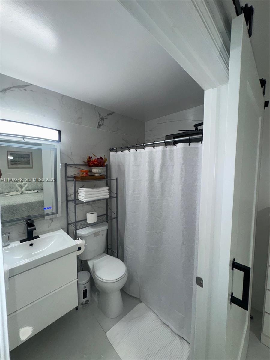 7965 Northwest 8th Street, Unit 23E Miami, FL 33126 - Photo 8 of 11 a bathroom with a toilet a sink and a mirror
