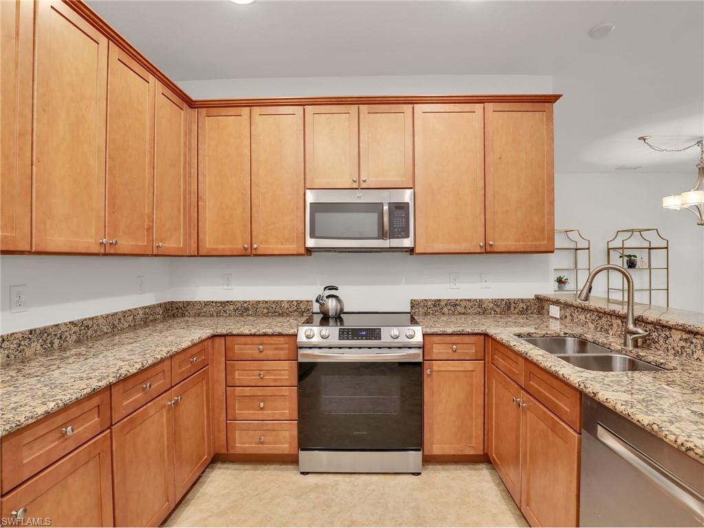 9066 Albion Lane North, Unit 5103 Naples, FL 34113 - Photo 13 of 40 a kitchen with stainless steel appliances granite countertop a sink stove and microwave