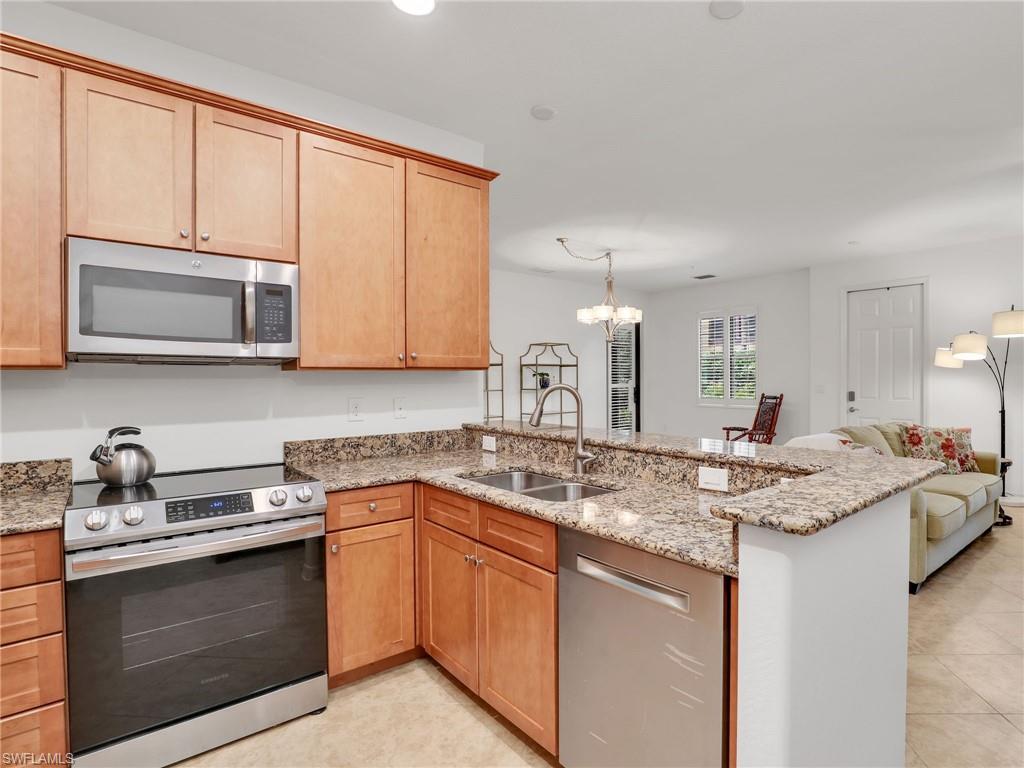 9066 Albion Lane North, Unit 5103 Naples, FL 34113 - Photo 14 of 40 a kitchen with stainless steel appliances granite countertop a sink stove and microwave
