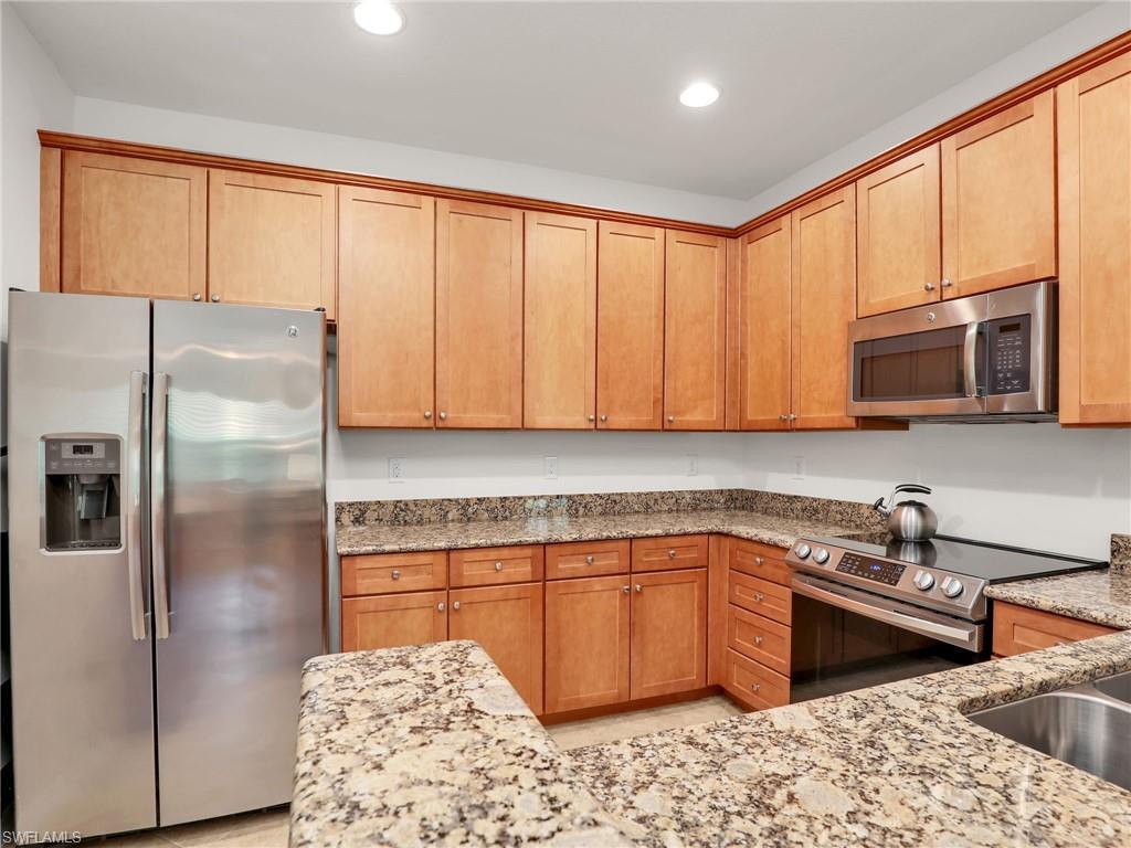 9066 Albion Lane North, Unit 5103 Naples, FL 34113 - Photo 15 of 40 a kitchen with stainless steel appliances granite countertop a stove a sink dishwasher a refrigerator and cabinets with wooden floor