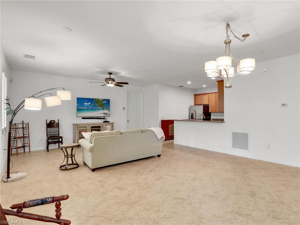 9066 Albion Lane North, Unit 5103 Naples, FL 34113 - Photo 10 of 40 a living room with furniture a chandelier and a flat screen tv