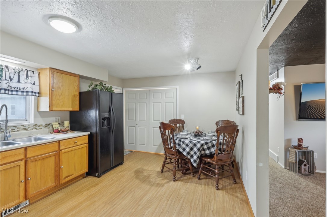 167 Birch Road Painesville, OH 44077 - Photo 11 of 49 Kitchen with black refrigerator with ice dispenser, a textured ceiling, sink, and light hardwood / wood-style flooring