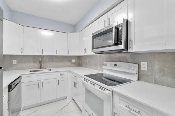 a kitchen with white cabinets sink and stainless steel appliances