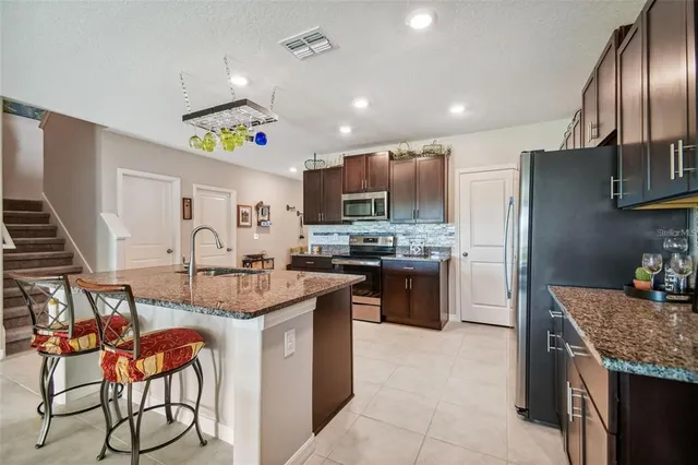 a kitchen with stainless steel appliances granite countertop a sink refrigerator and cabinets