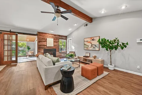 a living room with furniture and a large window with wooden floor