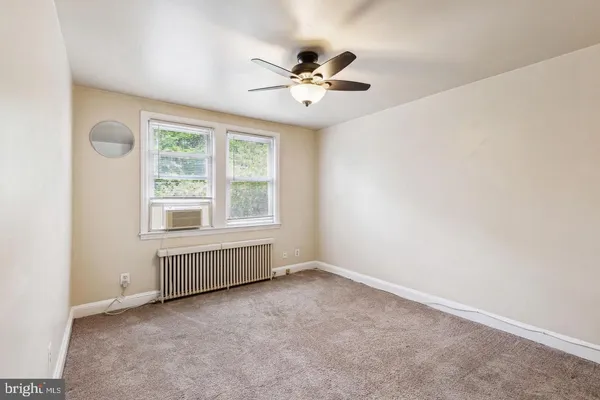 an empty room with windows and fan