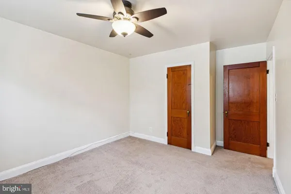 an empty room with closet and a chandelier fan