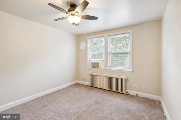 an empty room with chandelier fan and windows