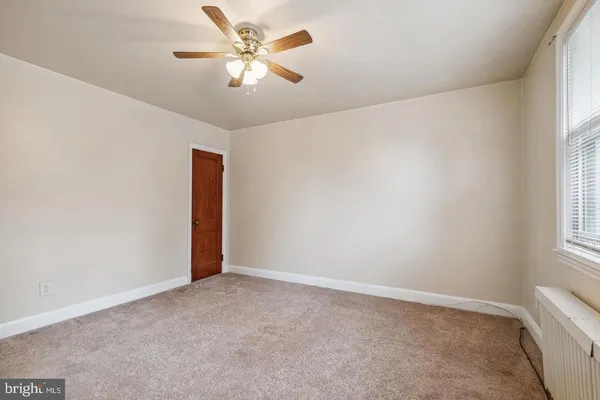 an empty room with a window and a fan